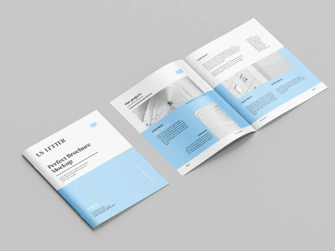 Open brochure titled 'US LETTER Perfect Brochure Mockup' with a white and light blue cover, lying on a gray surface, showing inside pages with text and images about architectural projects.