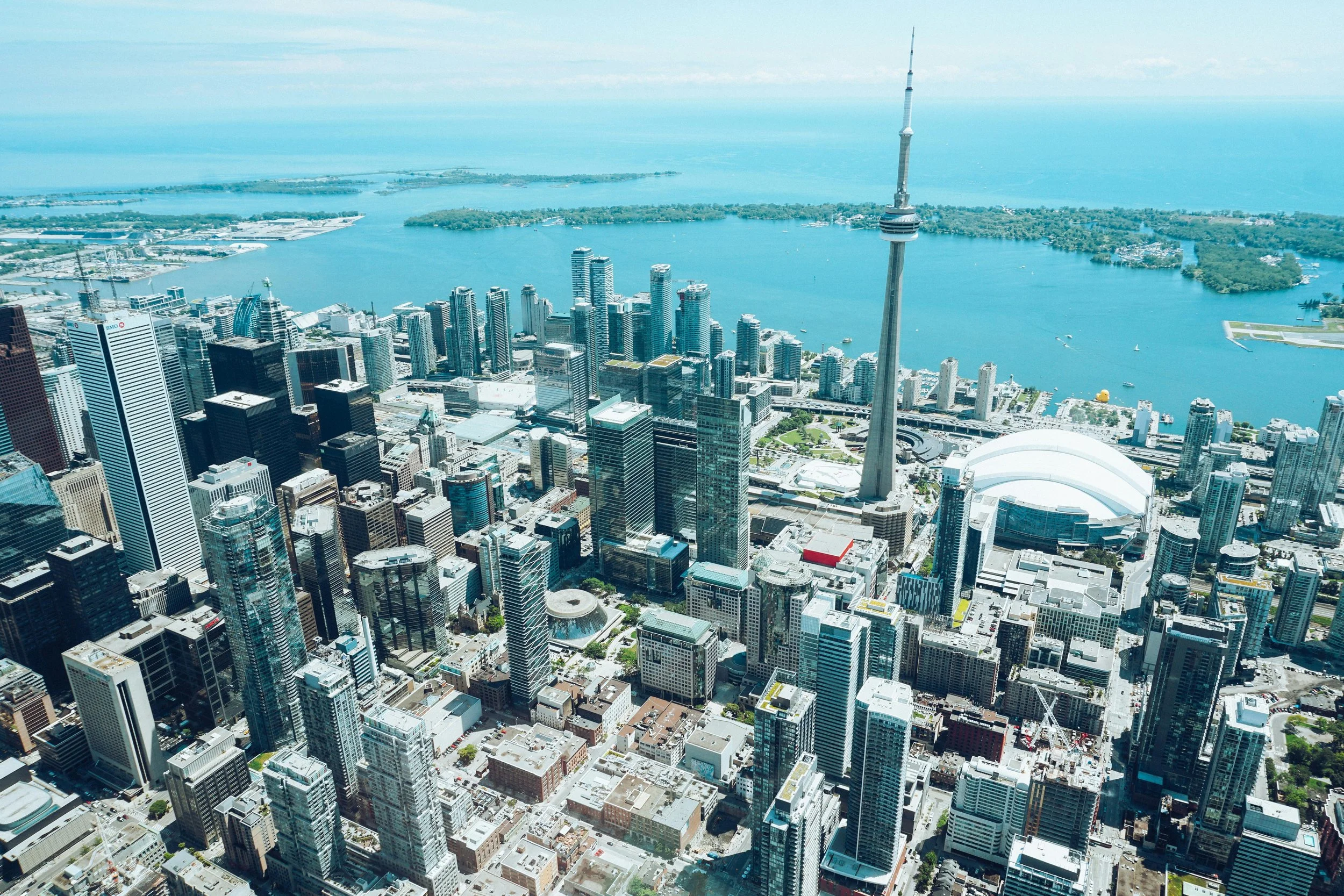 Aerial view of downtown Toronto with high-rise buildings and the CN Tower, overlooking Lake Ontario.