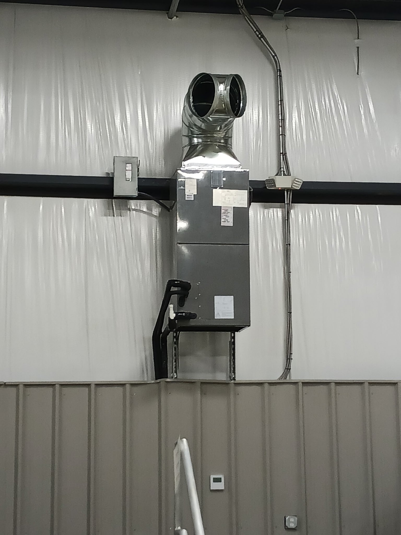 Industrial ventilation duct system mounted on wall inside a building.