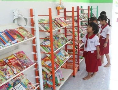 Grundschüler und Grundschülerinnen in rot-weißer Schuluniform in einer Schulbibliothek in einer vietnamesischen Grundschule