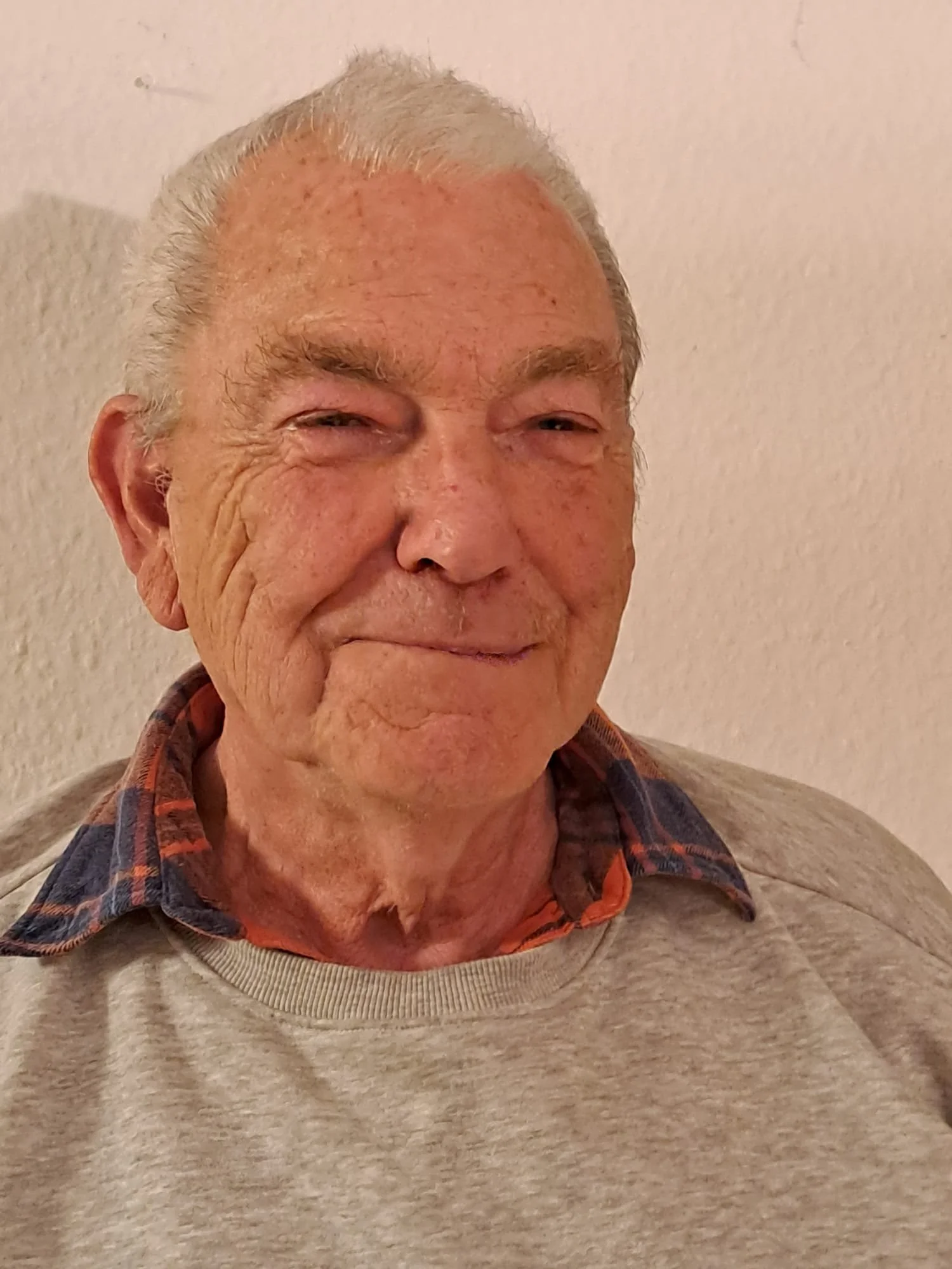 Ein älterer Mann mit weißen Haareb, der in die Kamera lächelt