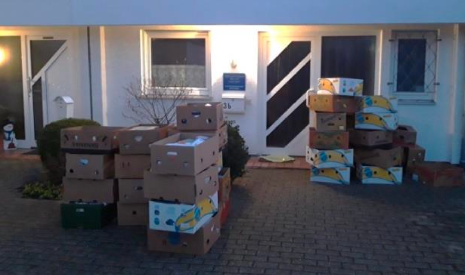 Vor einem Hauseingang stehen zahlreiche gepackte Umzugskartons und Bananenkisten