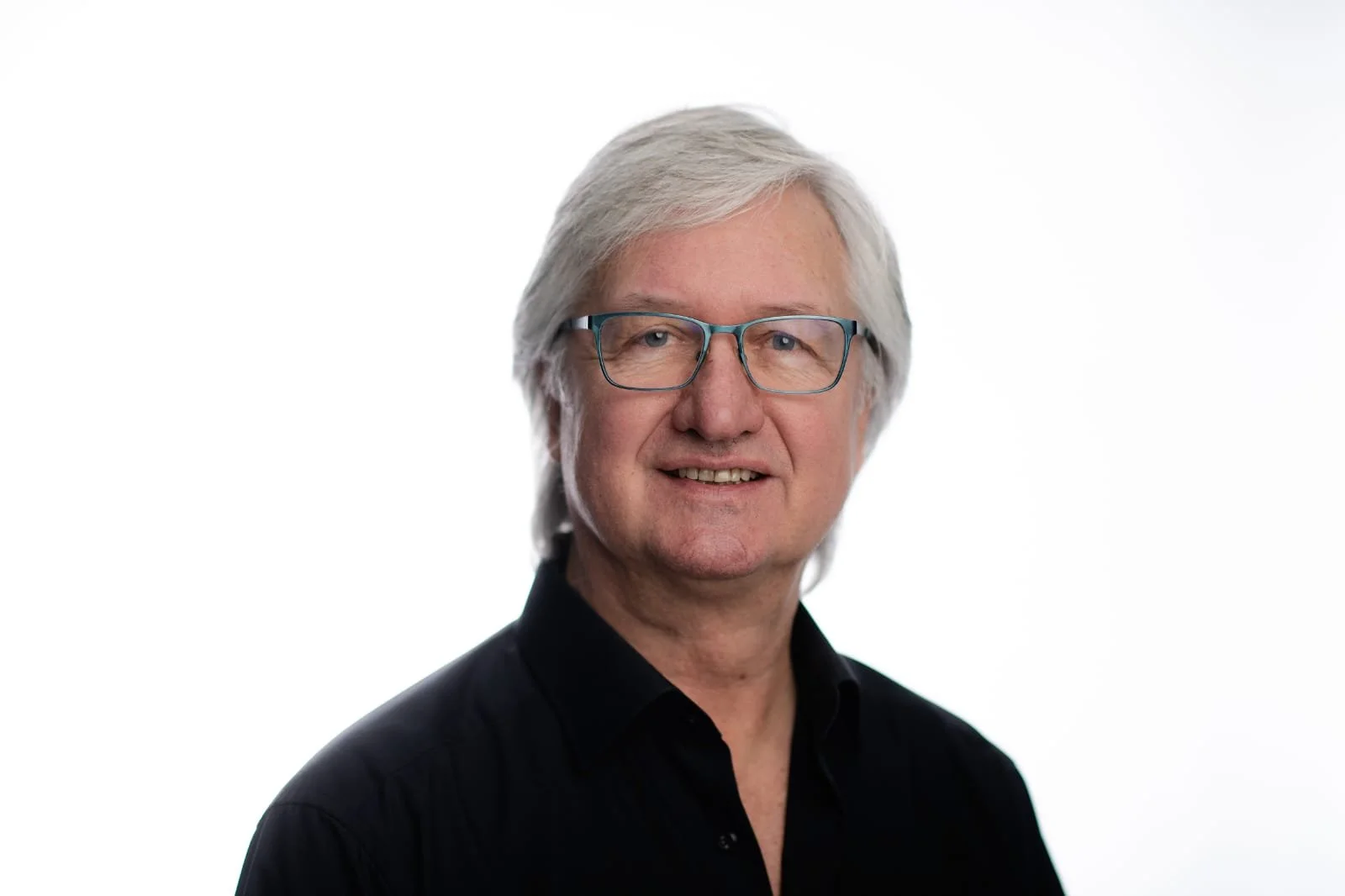 Ein Mann mit grauen Haaren und Brille lächelt in die Kamera