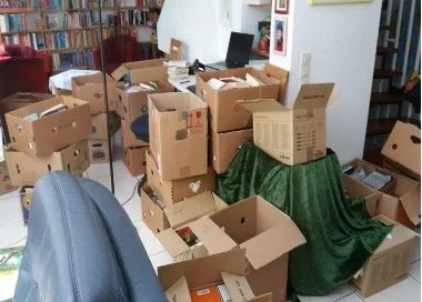 Umzugskartons mit Büchern darin stehen in einem Wohnzimmer