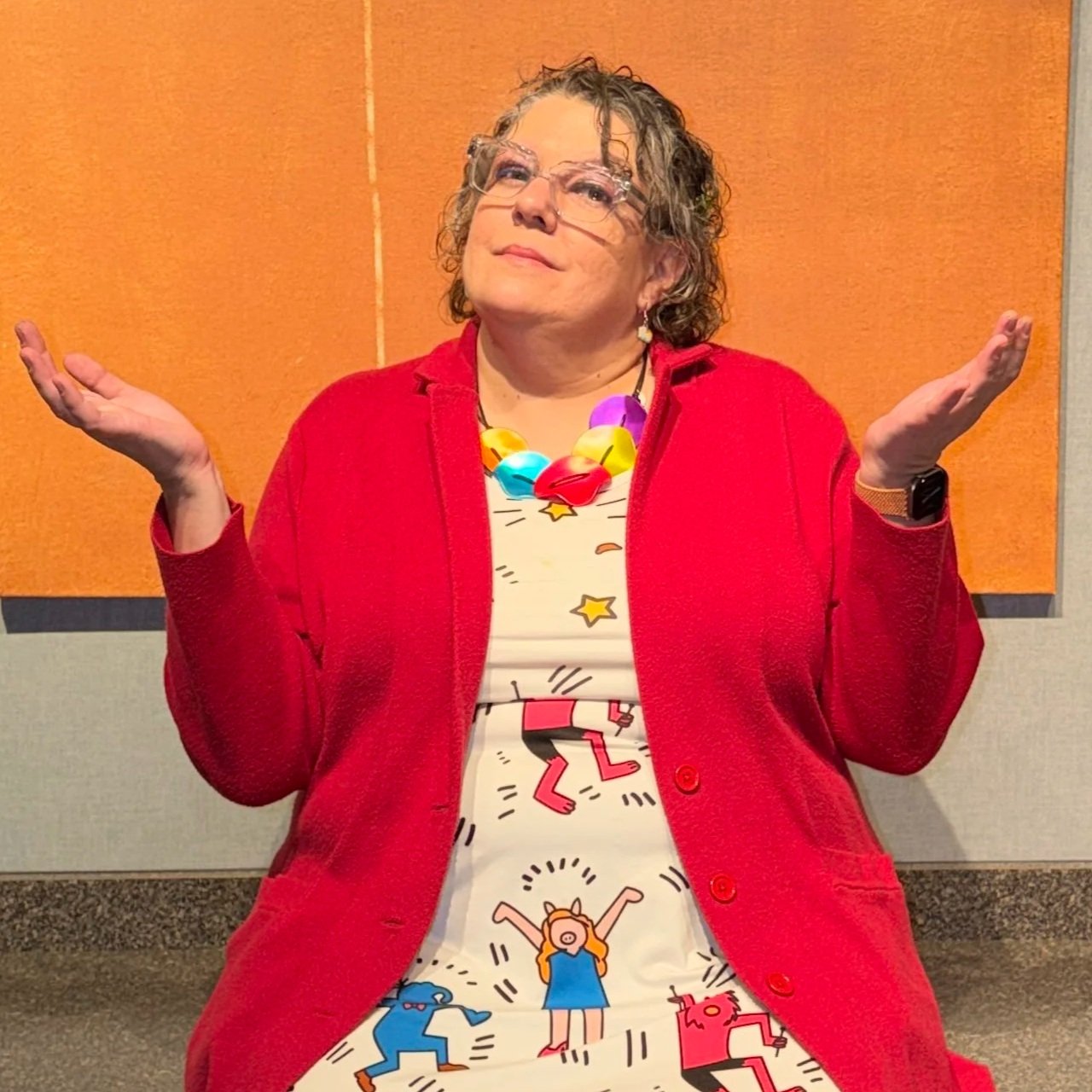 Rabbi Elisa Koppel sitting with her hands in a welcoming "why" gesture.