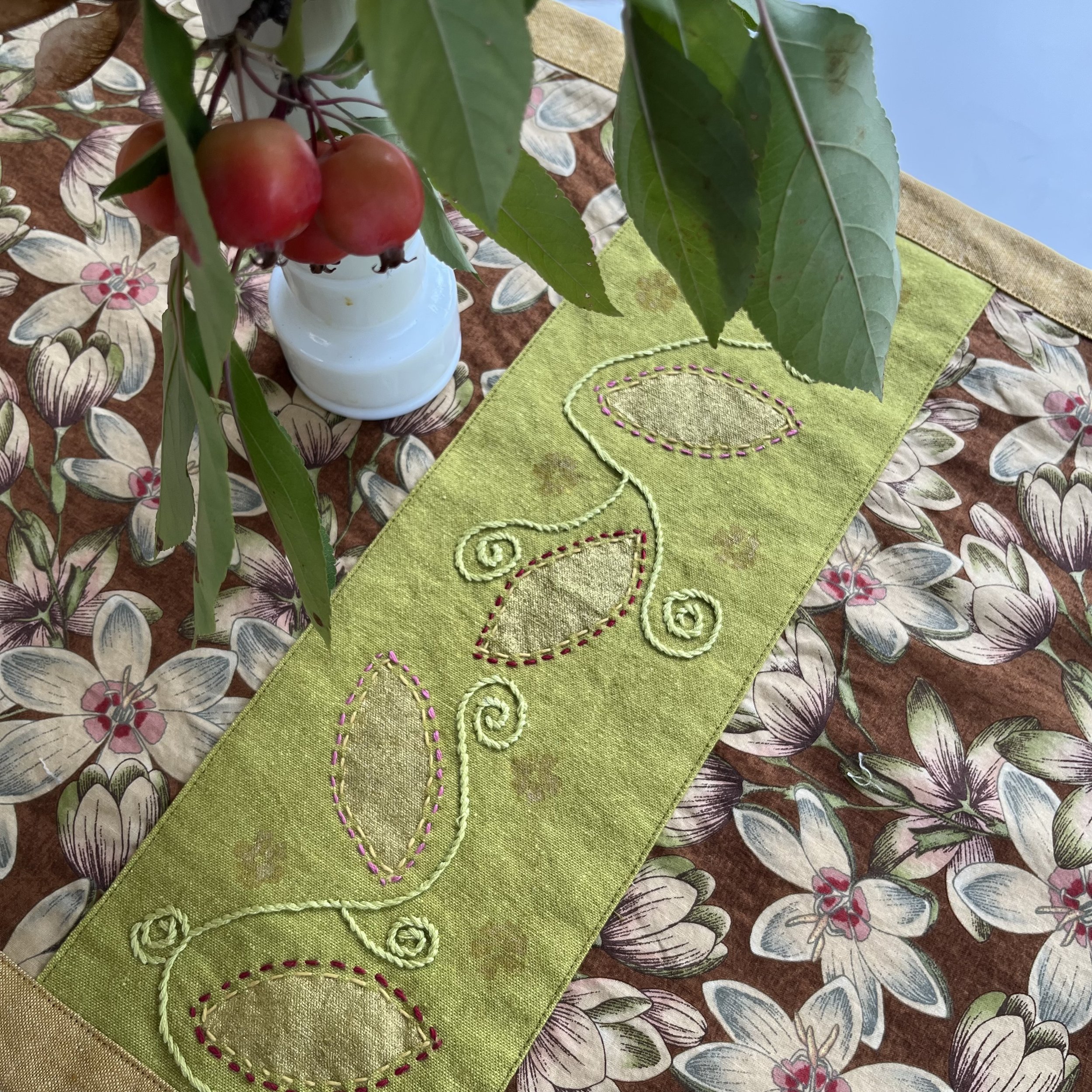 Green and gold table runner section with hand printed gold leaves and embroidery.