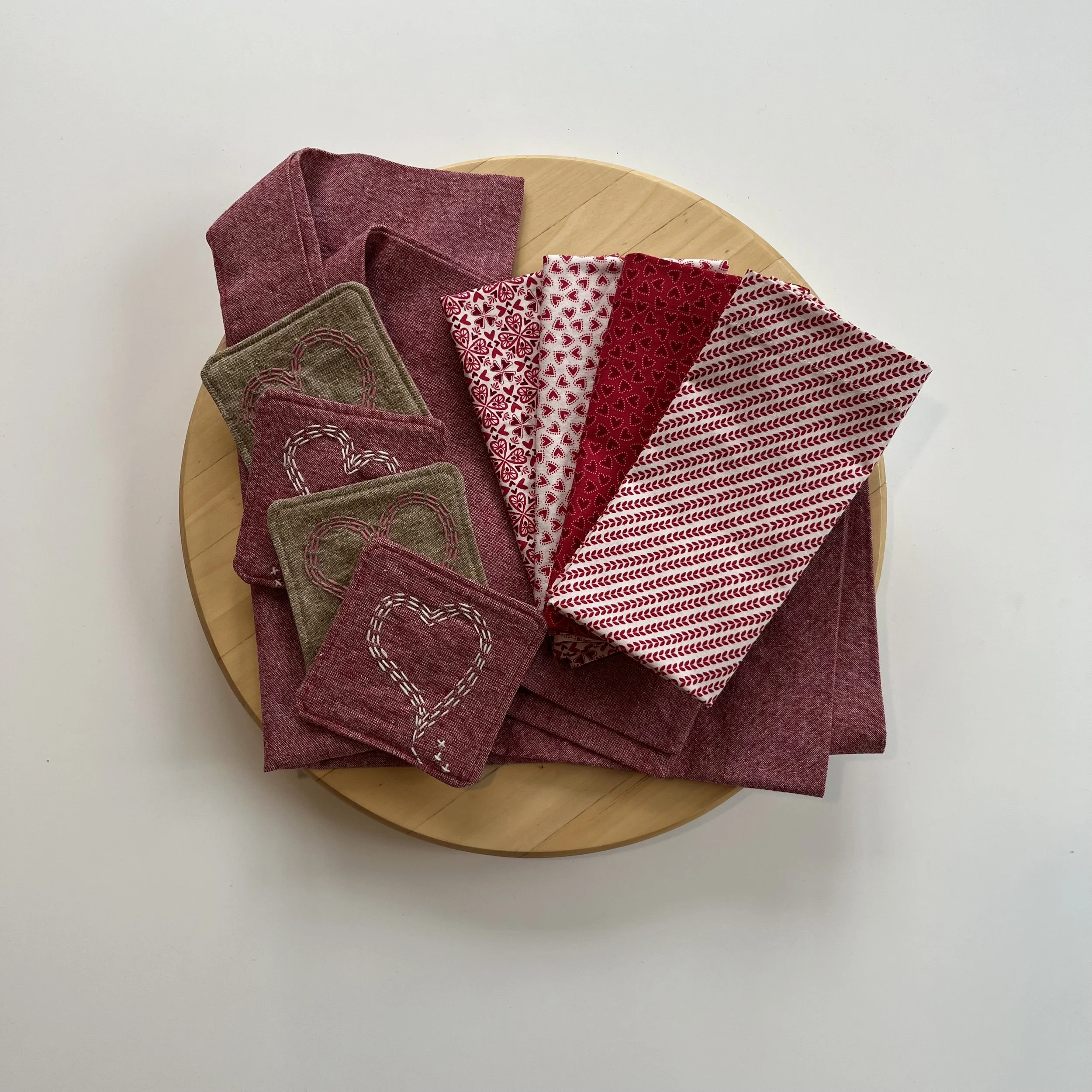 Valentine's Day-themed cotton fabric napkins and small fabric coasters with hand stitched heart designs.