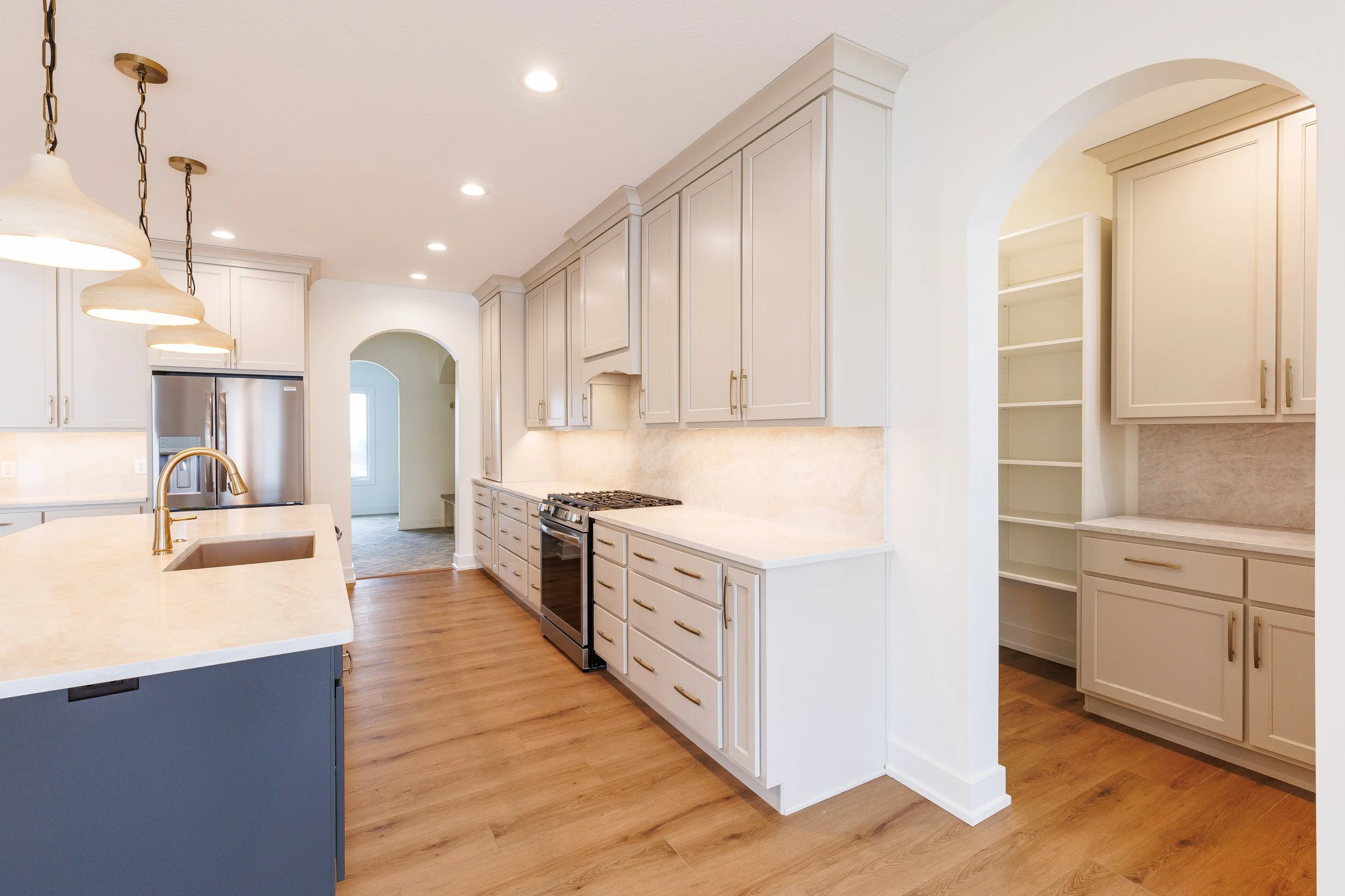Photography of a new luxury home build. Features beautiful countertops, arched entryways, kitchen island, and pantry