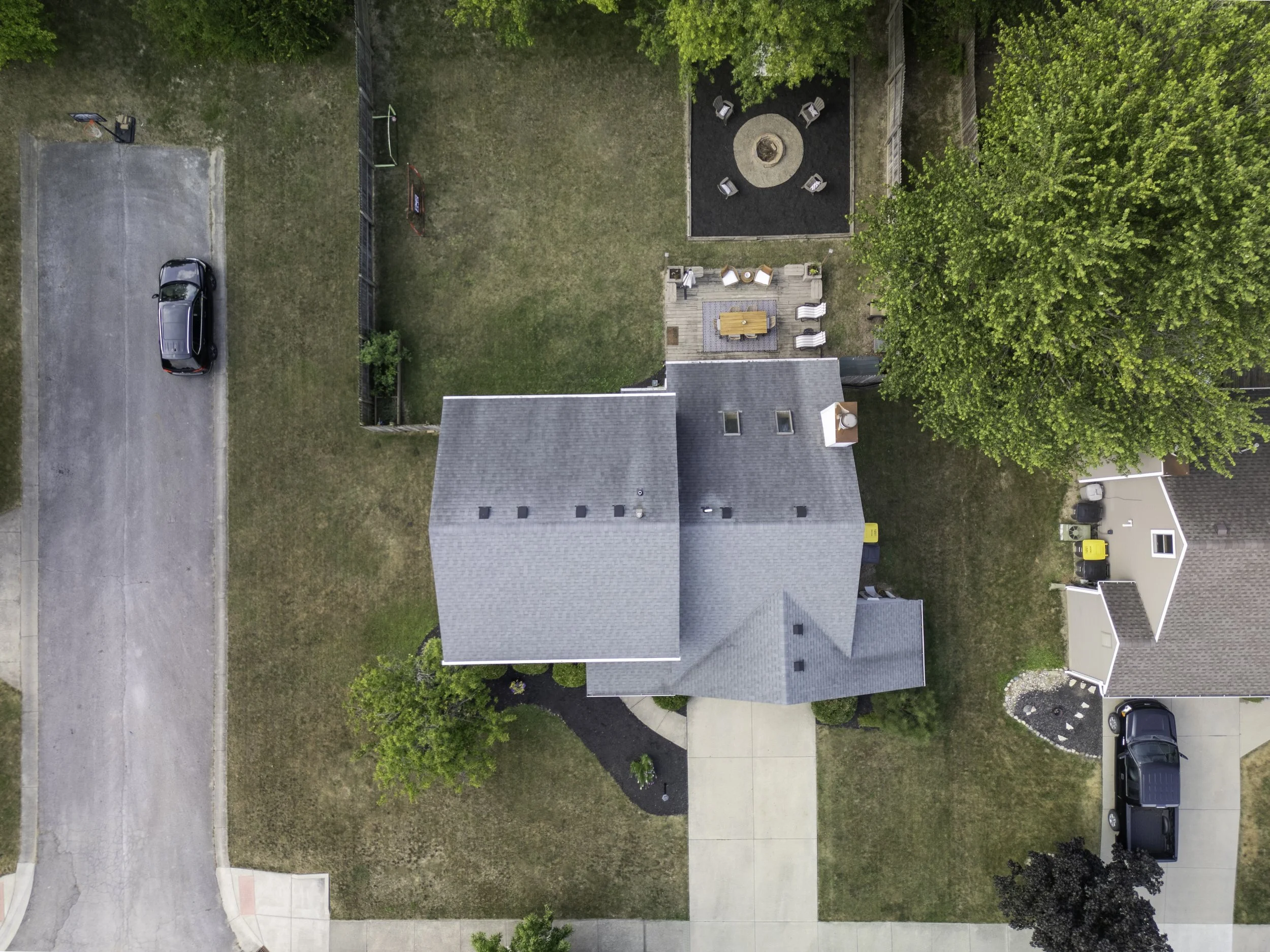 Overhead aerial drone photo of a single family home with plenty of parking. Home features amazing outdoor living space, large driveway, nice landscaping, and room to park on the closed street on the left side.