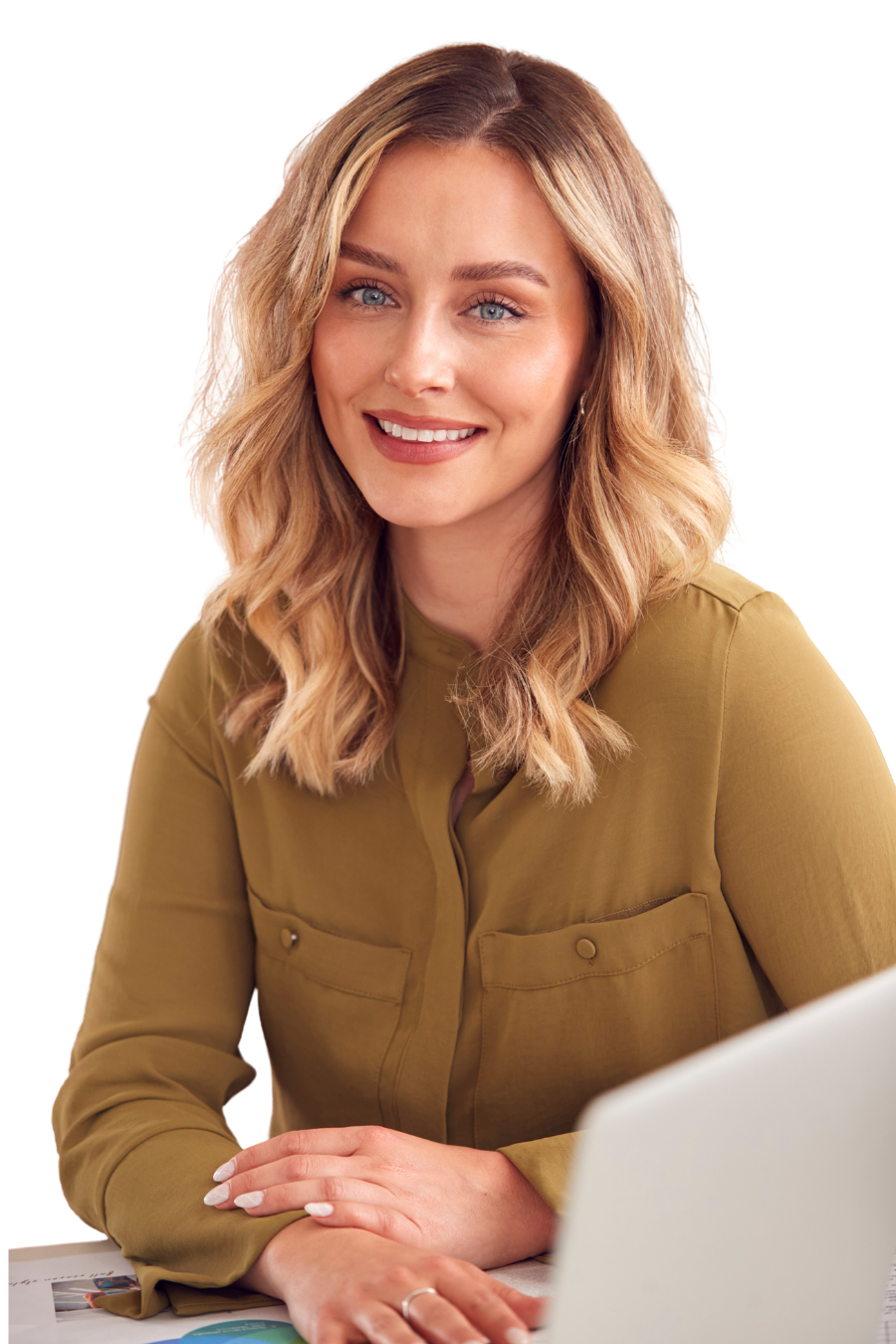 A woman with blonde wavy hair smiling while sitting at a desk with a laptop.
