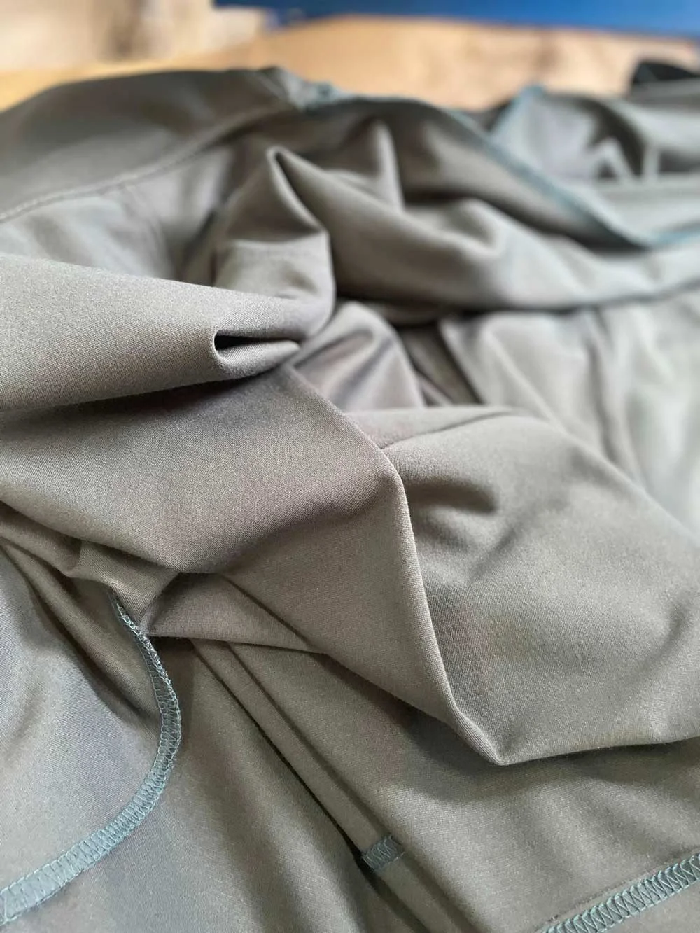 Close-up of crumpled beige and gray fabric or clothing with visible stitching.