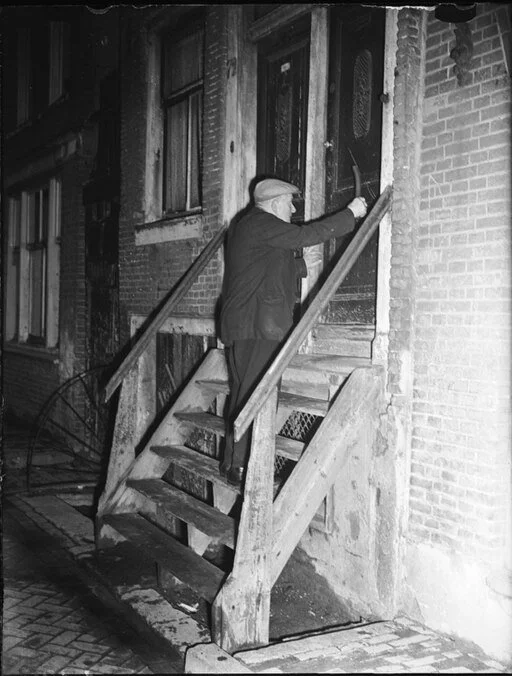 a knocker upper man tapping on the front door of a factory working in the early morning hours.