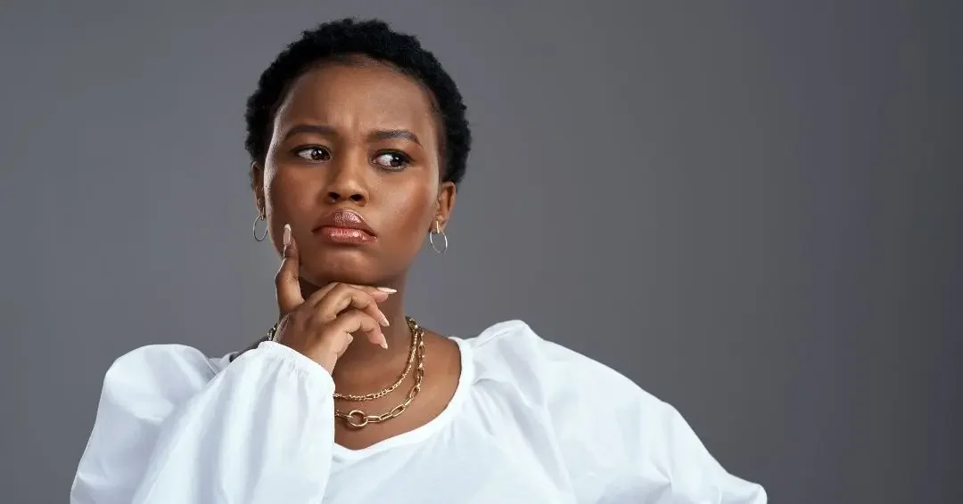 Manager sitting with her hand at her chin, looking uncertain as she considers questions from her boss before a high-stakes meeting.