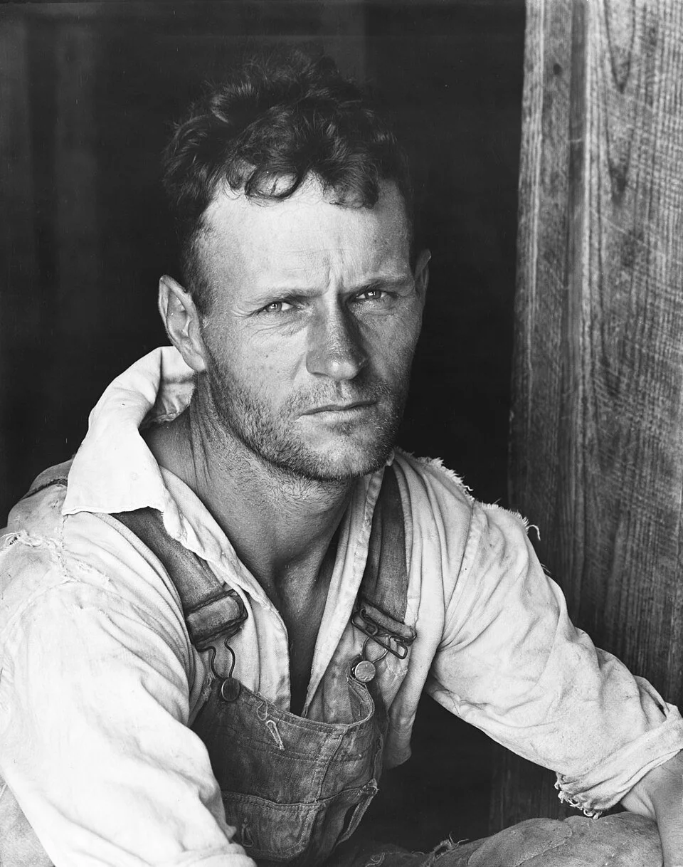 Close up black and white portrait of Floyd Burroughs a cotton sharecropper in Hale County Alabama wearing canvas work overalls and a light colored shirt.