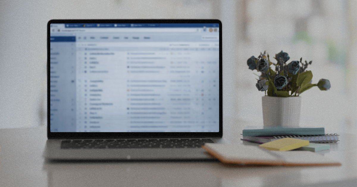 Blurred laptop inbox on a desk late at night, showing open work and mental load.