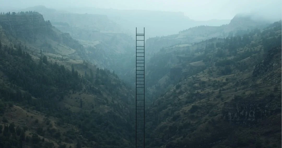 A surreal image of a tall, thin black ladder rising vertically from the center of a misty canyon between dark, rugged mountains.