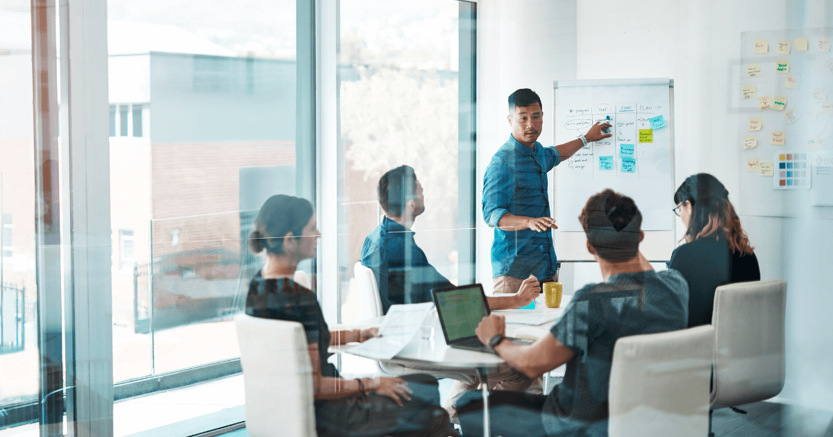 Manager leading a team meeting while outlining work standards and decision criteria on a whiteboard, illustrating how clarity and structure support team execution.