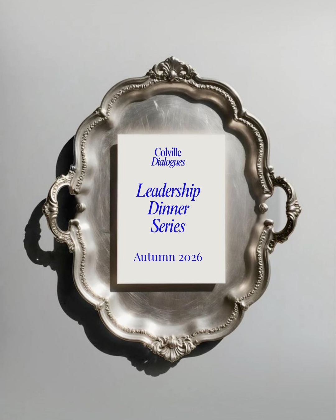 Invitation card titled 'Colville Dialogues Leadership Dinner Series Autumn 2026' on a silver ornate tray with shadows cast on a light background.