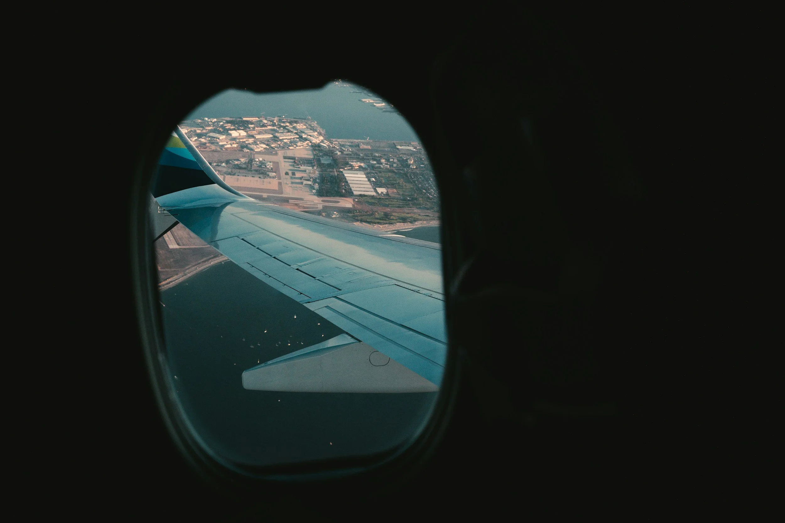 A French Voyage client's view from the airplane wing on the way to Paris. The landscape is seen through an airplane window from inside the aircraft.