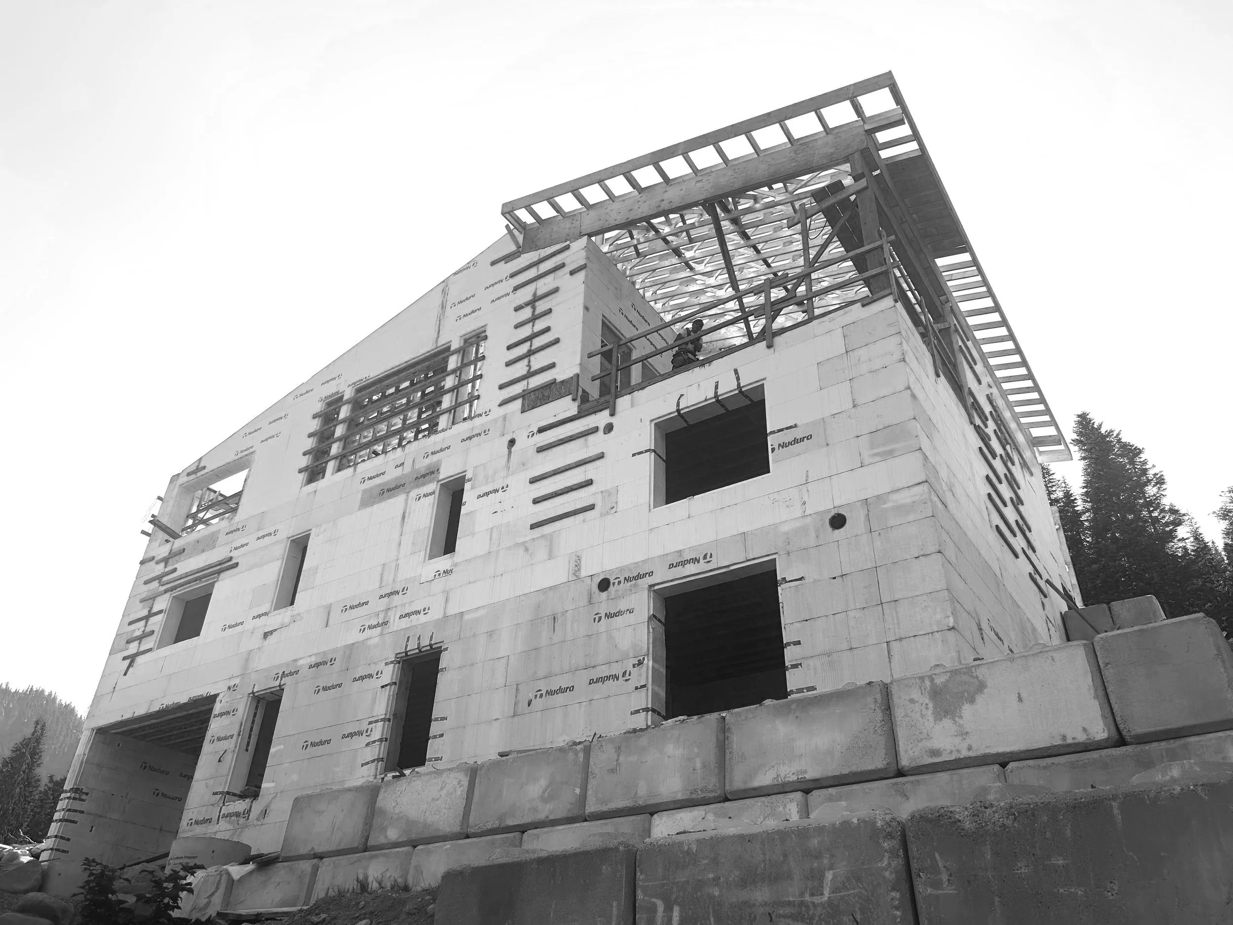 Black and white photo of a multi-story building under construction with exposed framing and ICF framing.