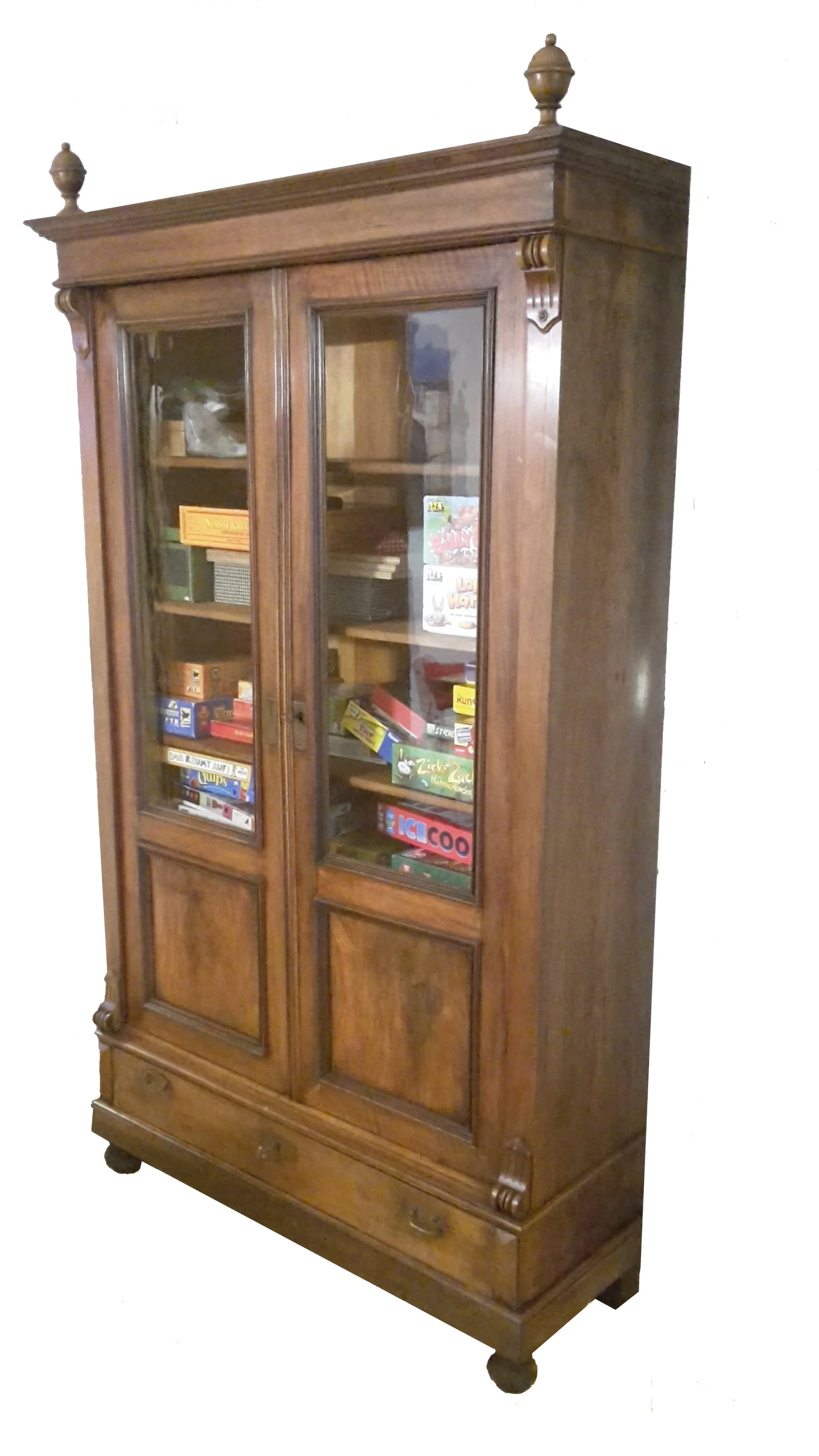 Historismus-Glasvitrinenschrank aus Massivholz mit zwei verglasten Türen, Innenböden, gedrechselten Zierelementen und Schublade im unteren Bereich.