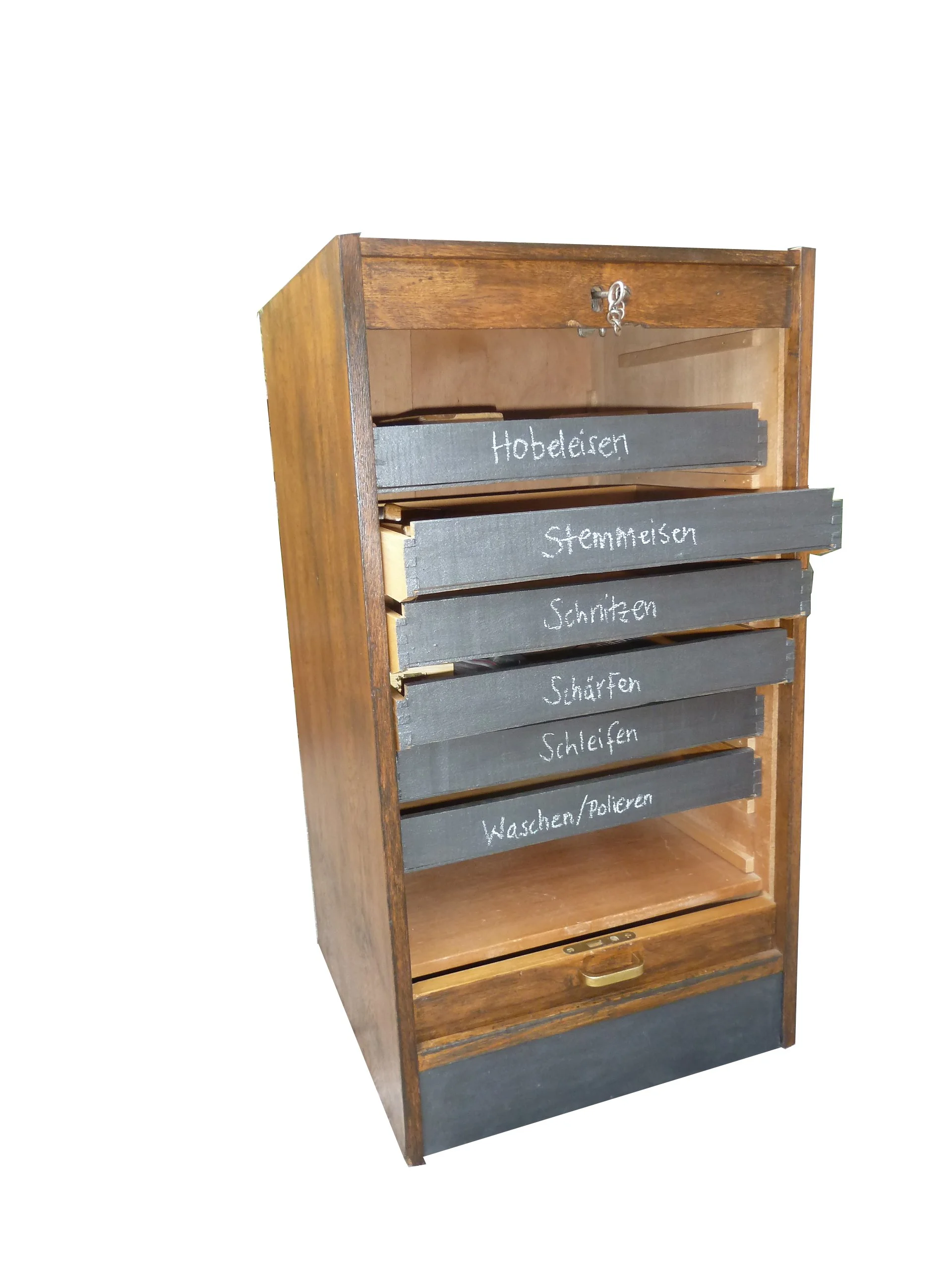 Kleines hölzernes Werkzeugschränkchen mit Jalousiefront, beschrifteten Schubladen und Scharnierklappe im unteren Bereich.