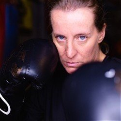 Poster image. A woman stares down camera moodily from behind boxing gloves