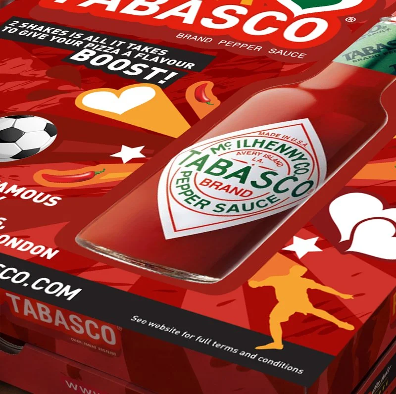 A box of Tabasco brand pepper sauce with a label showing it's made in the USA, with colorful illustrations including a soccer ball, a chili pepper, and a silhouette of a soccer player.