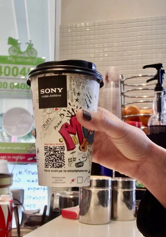 a hand holding a disposable AD-cup coffee