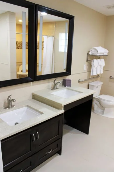 Bathroom with double sinks, a large mirror, towel racks, and a toilet.