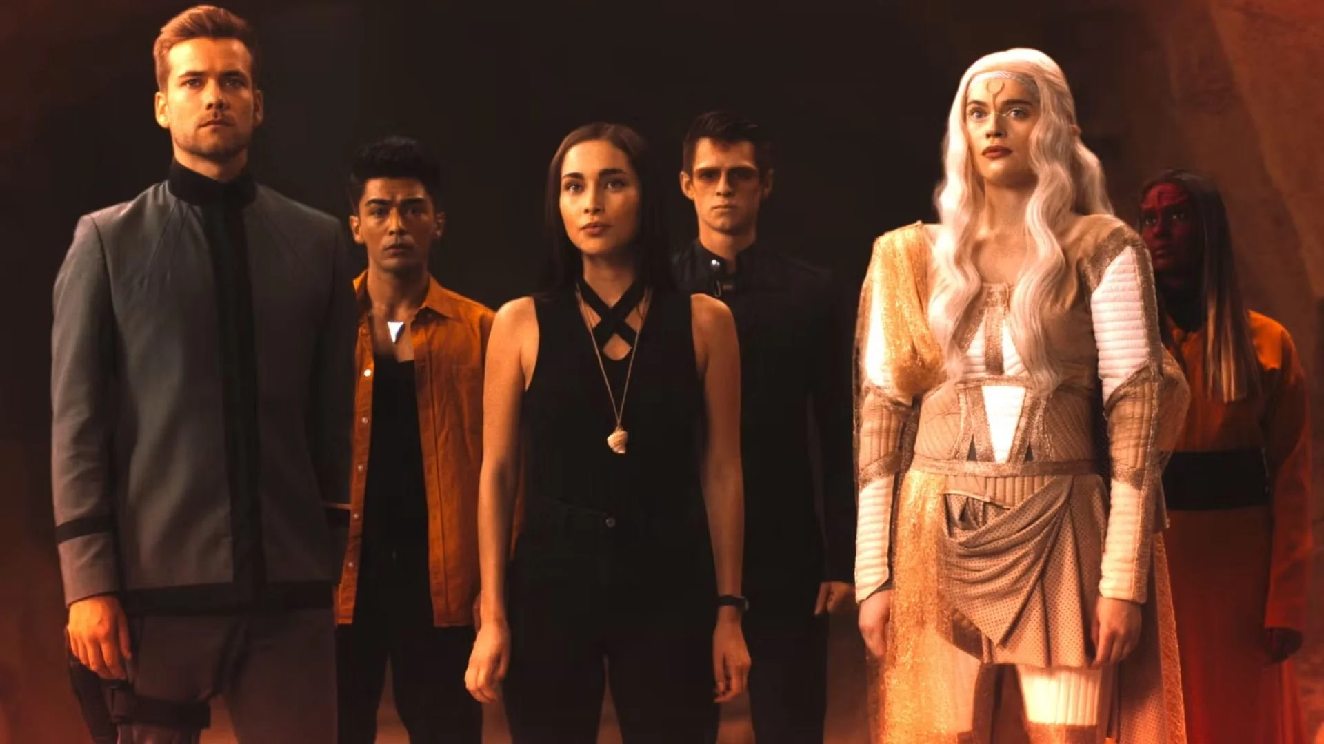 Group of six characters from the movie 'Dune' standing together in a dark room, featuring a mix of serious and neutral expressions, with medieval and futuristic inspired clothing and hairstyles.
