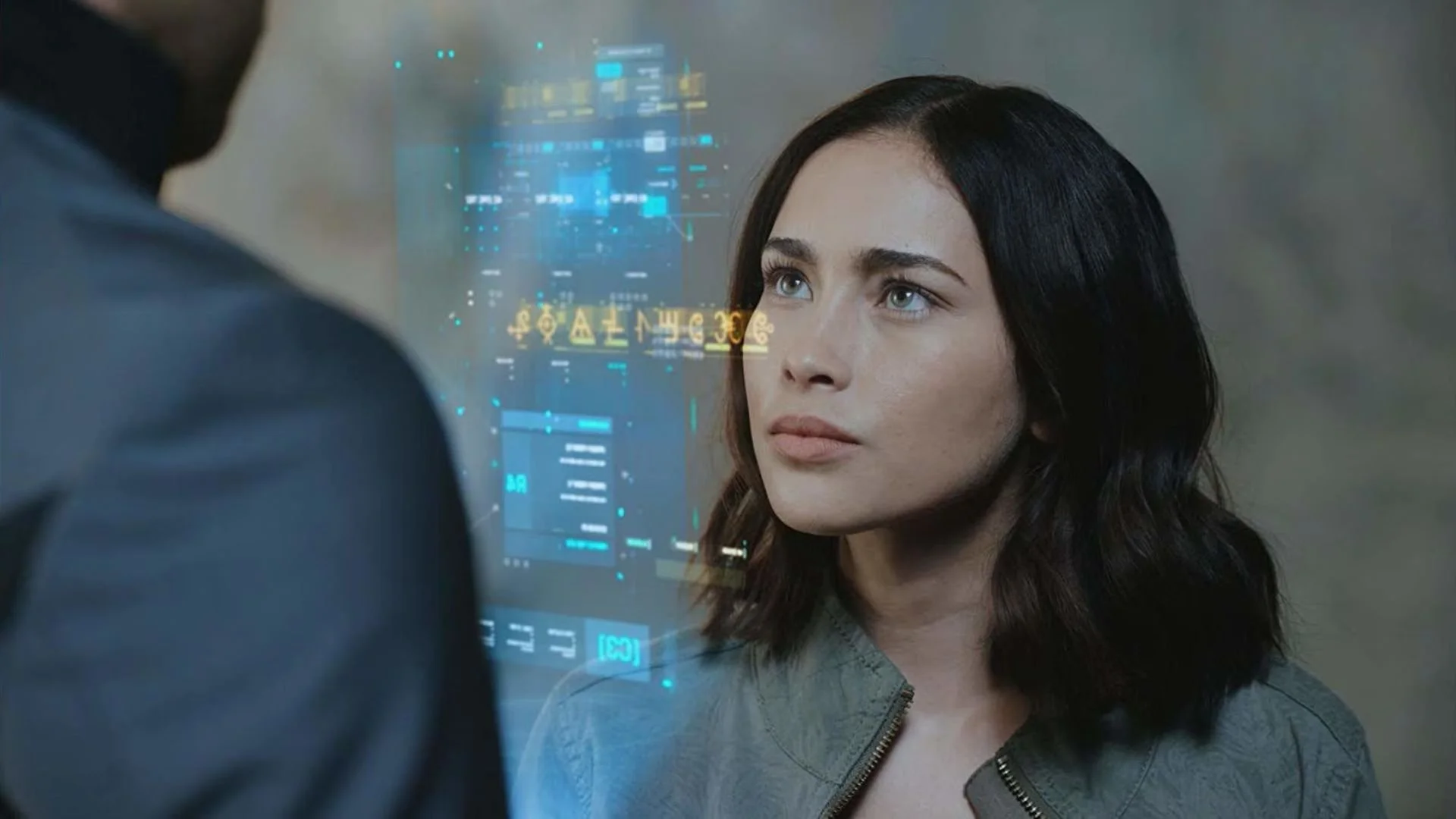 A woman with dark hair and blue eyes looks at a person with blurred features, with holographic digital data floating between them.