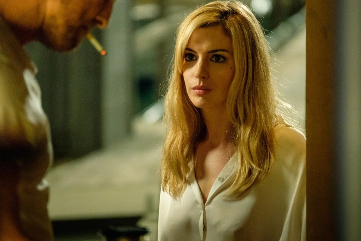 A woman with long blonde hair looking at a man with a cigarette in his mouth.