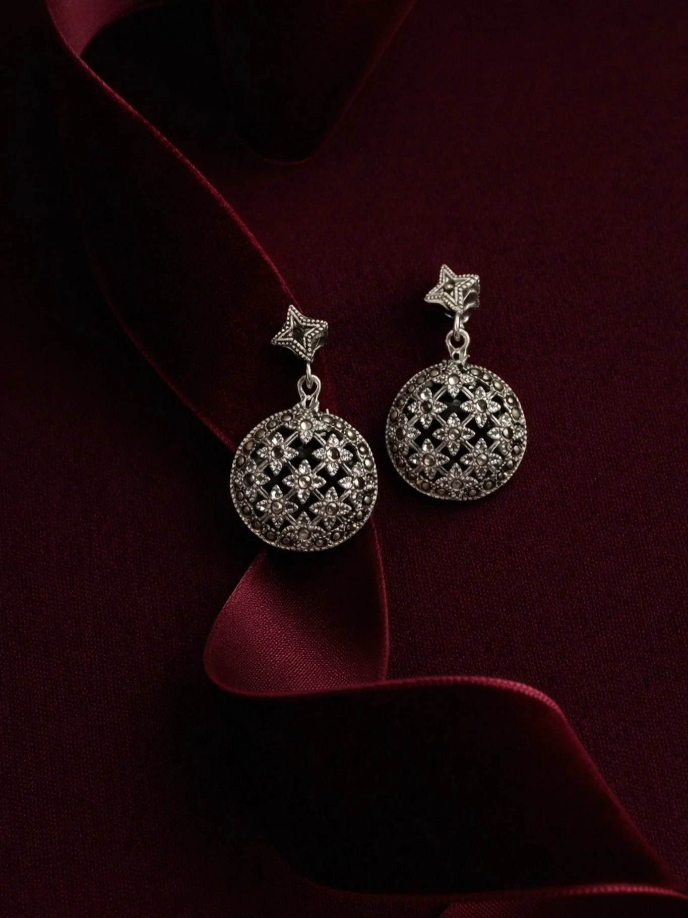 Elmina Earrings
&bull;Defined by architectural balance and quiet symbolism.
The open dome echoes historic geometric medallions, while the eight-pointed star above represents harmony and intention. Crafted in oxidized silver with marcasite, each pair 