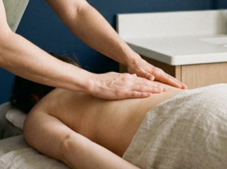 hands applying massage cream to back