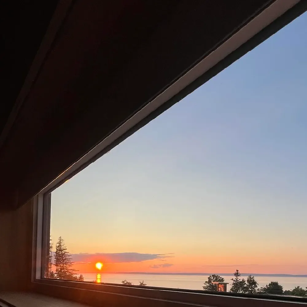 Sunset view through a window showing the sky, water, and trees.