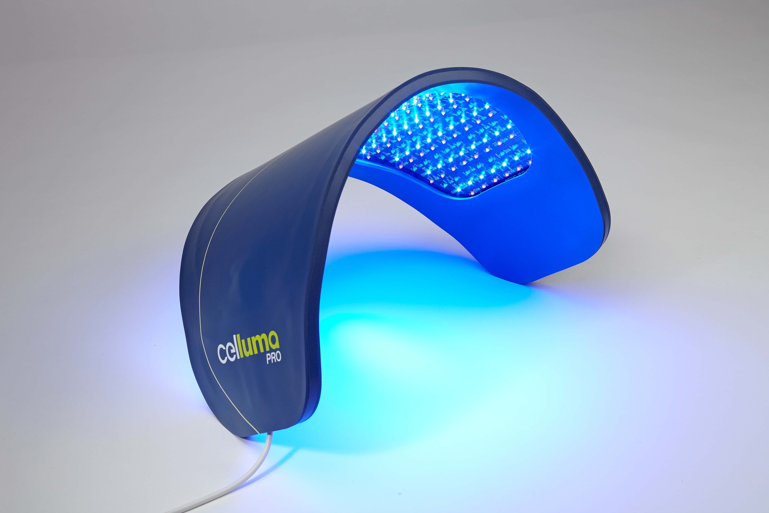 Blue handheld device named 'celluma PRO' with LED lights emitting blue light, designed for skin treatment or therapy, on a plain white surface.