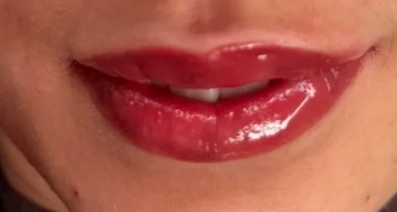 Nahaufnahme von einem Lächeln mit roten, glänzenden Lippen.