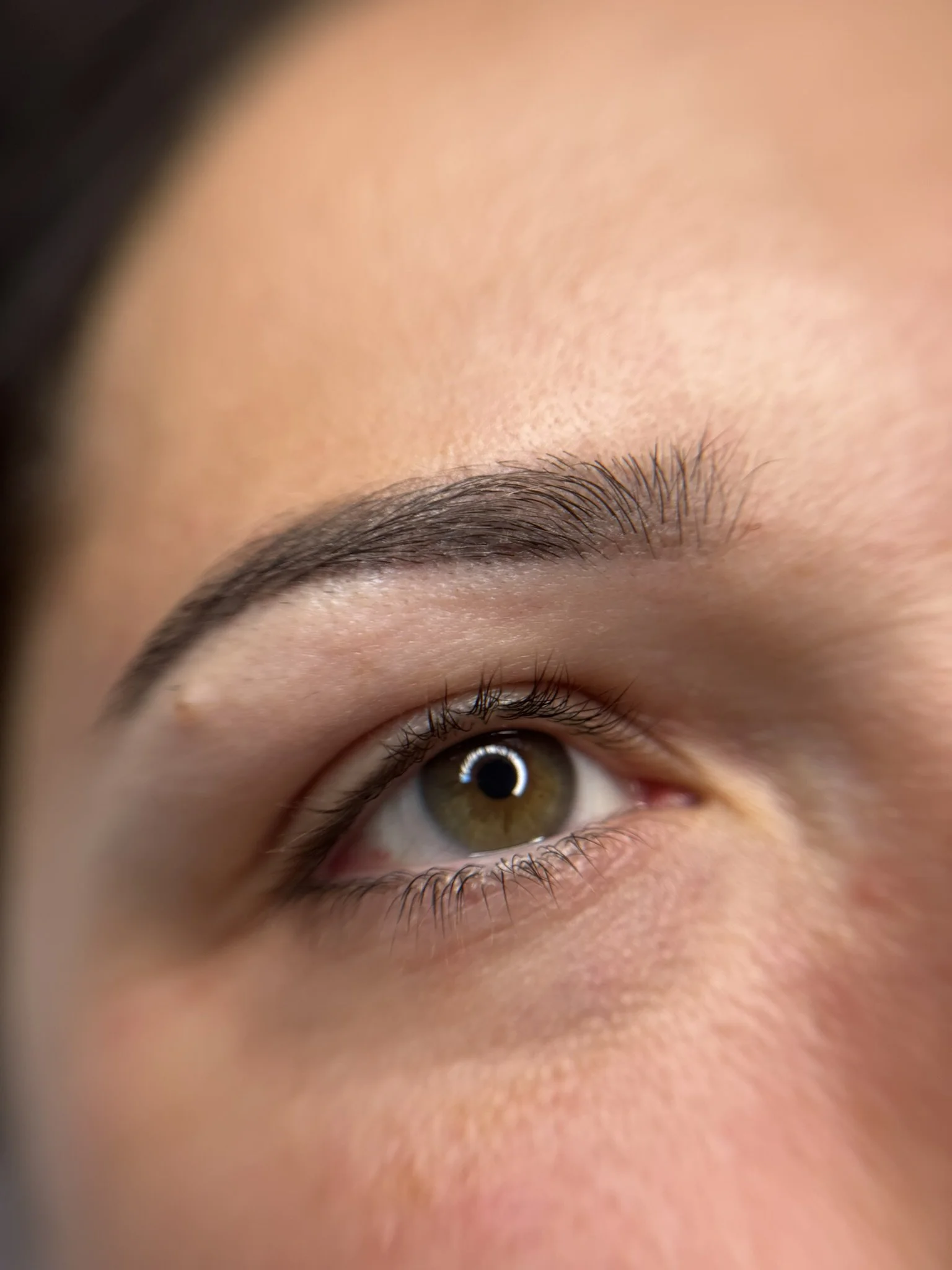 Nahaufnahme eines menschlichen Auges mit braunem Iris, hellem Haut und dichten Wimpern.