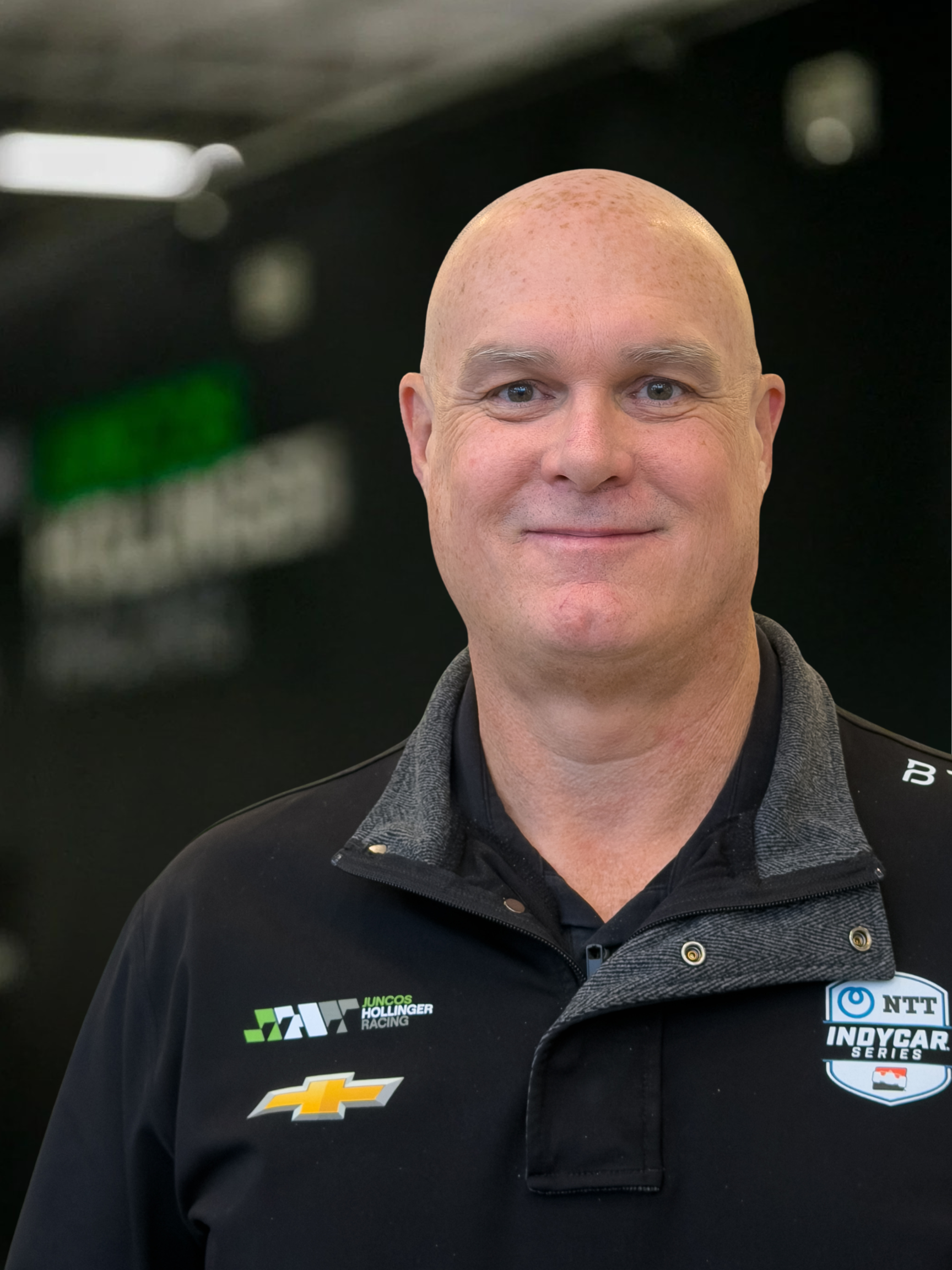 Image of Steve Sudler of Juncos Hollinger Racing in front of a Juncos trailer that is blurred