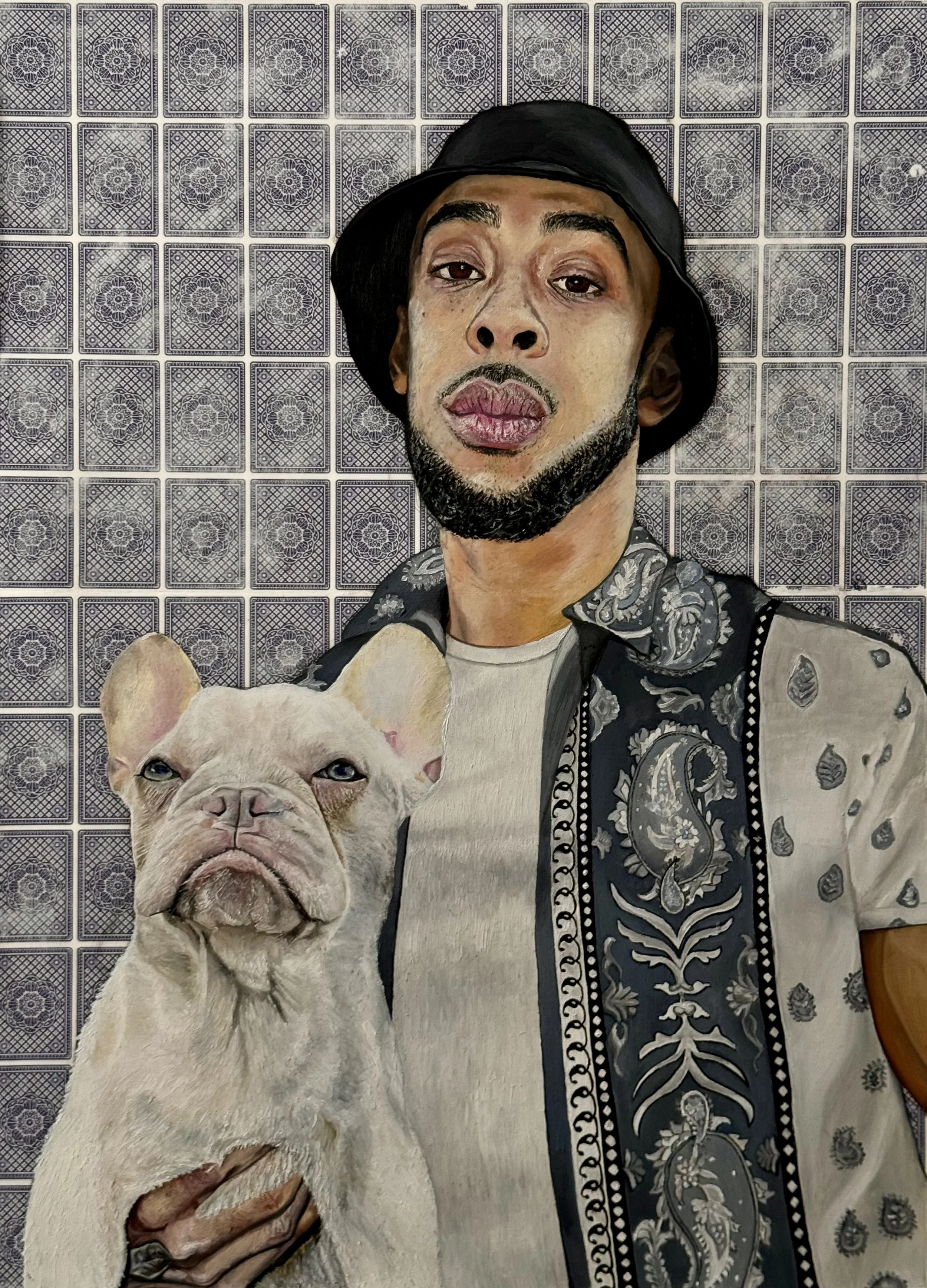 An oil painting of a man with a beard, wearing a hat and patterned shirt, holding a white bulldog, against a background of decorative playing cards.