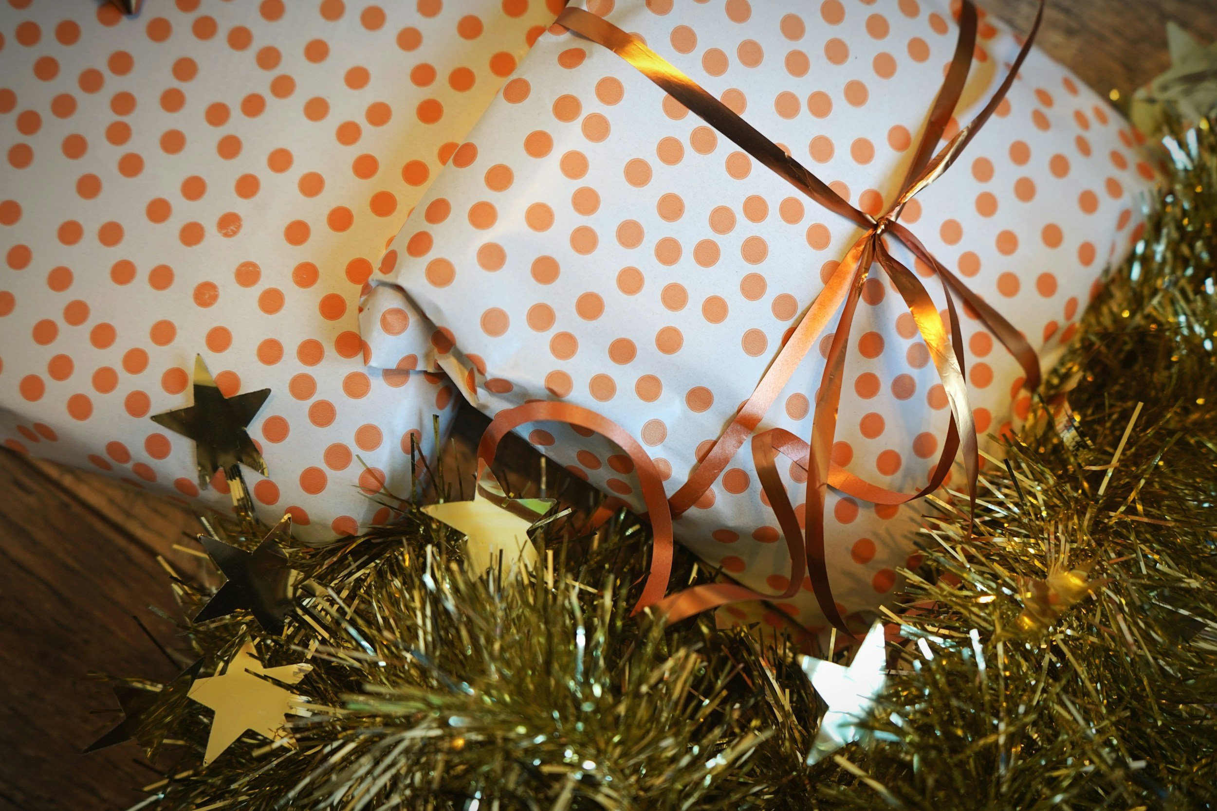 Image of a Christmas present with gold ribbon and spots by a tree