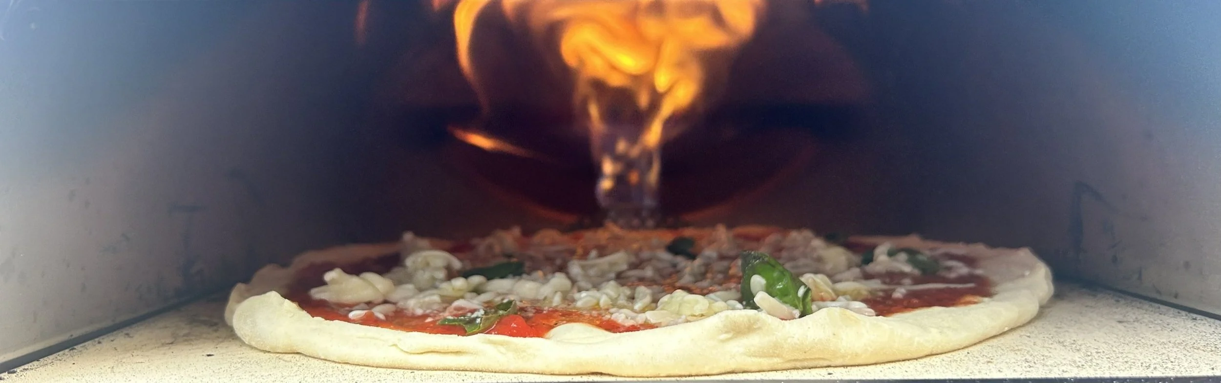 Pizza in an oven with flames above
