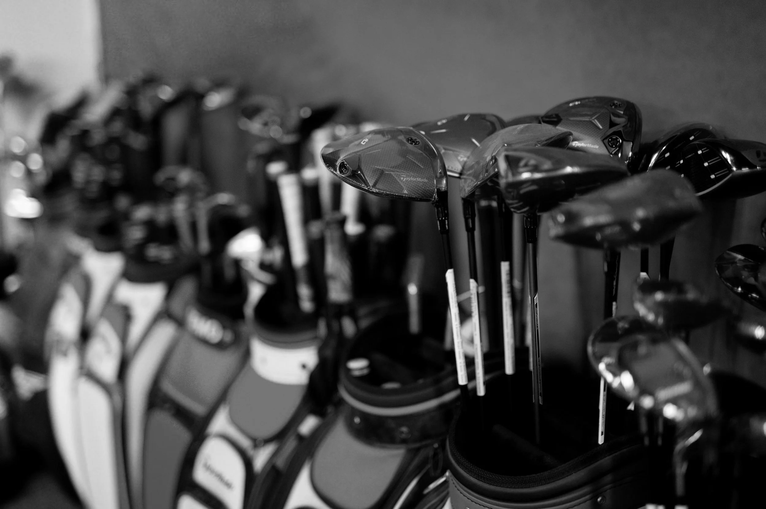 Golf clubs organized in a rack, with clubheads facing outward, in a golf shop or golf course pro shop.