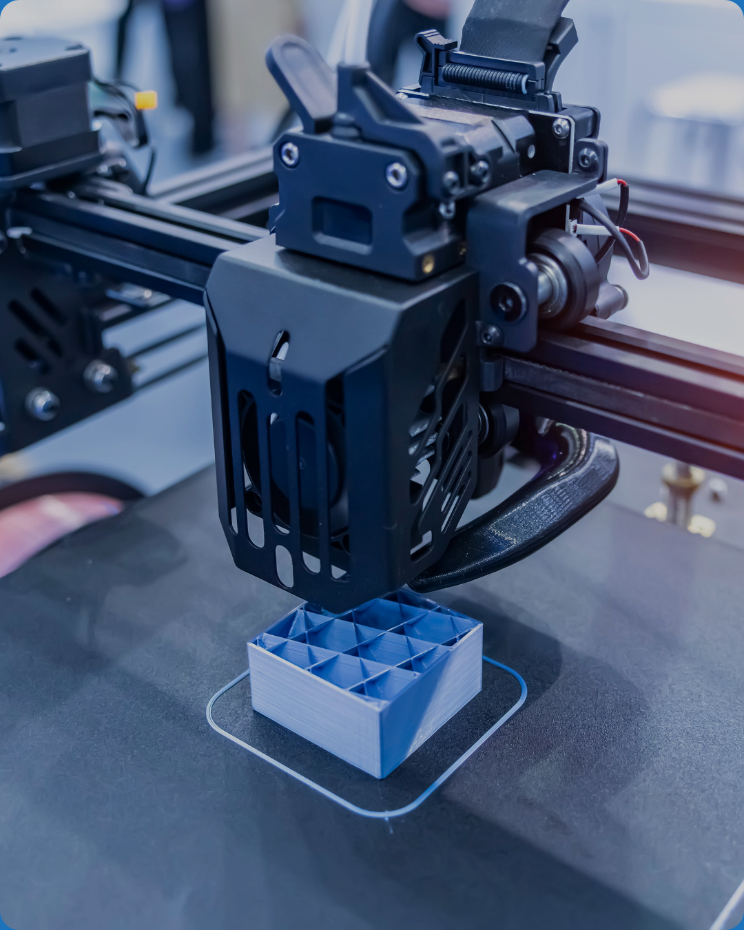 A 3D printer printing a small, blue, lattice-structured object on a black surface.