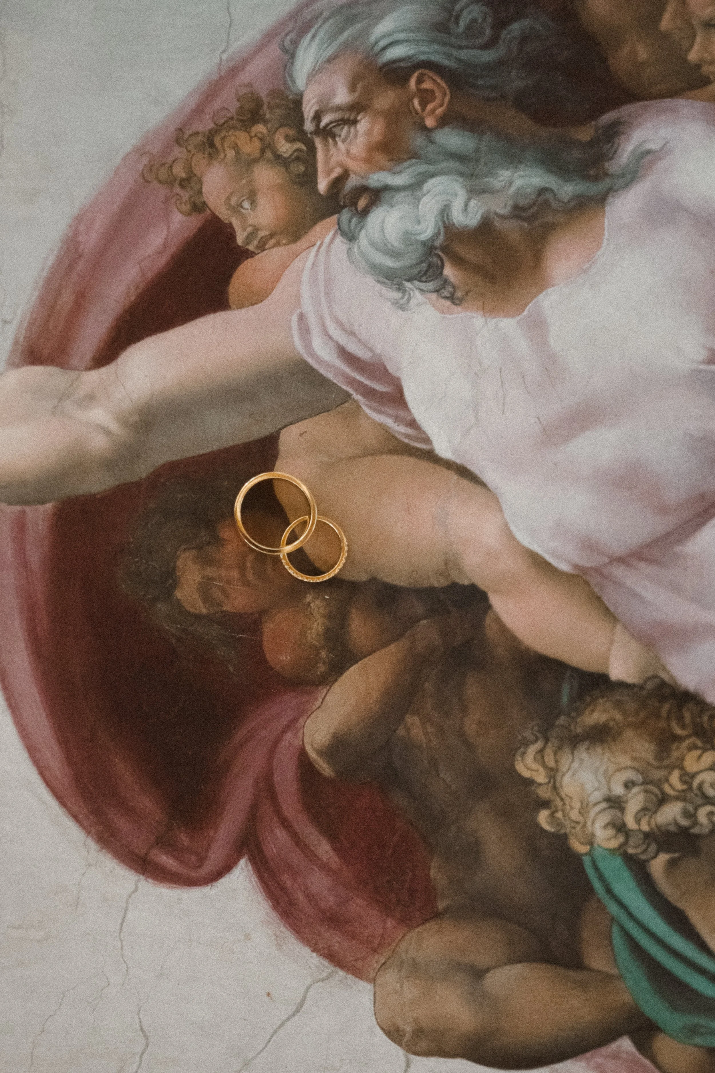Close-up of a painting of God and Jesus, with two gold rings resting on Jesus' chest.