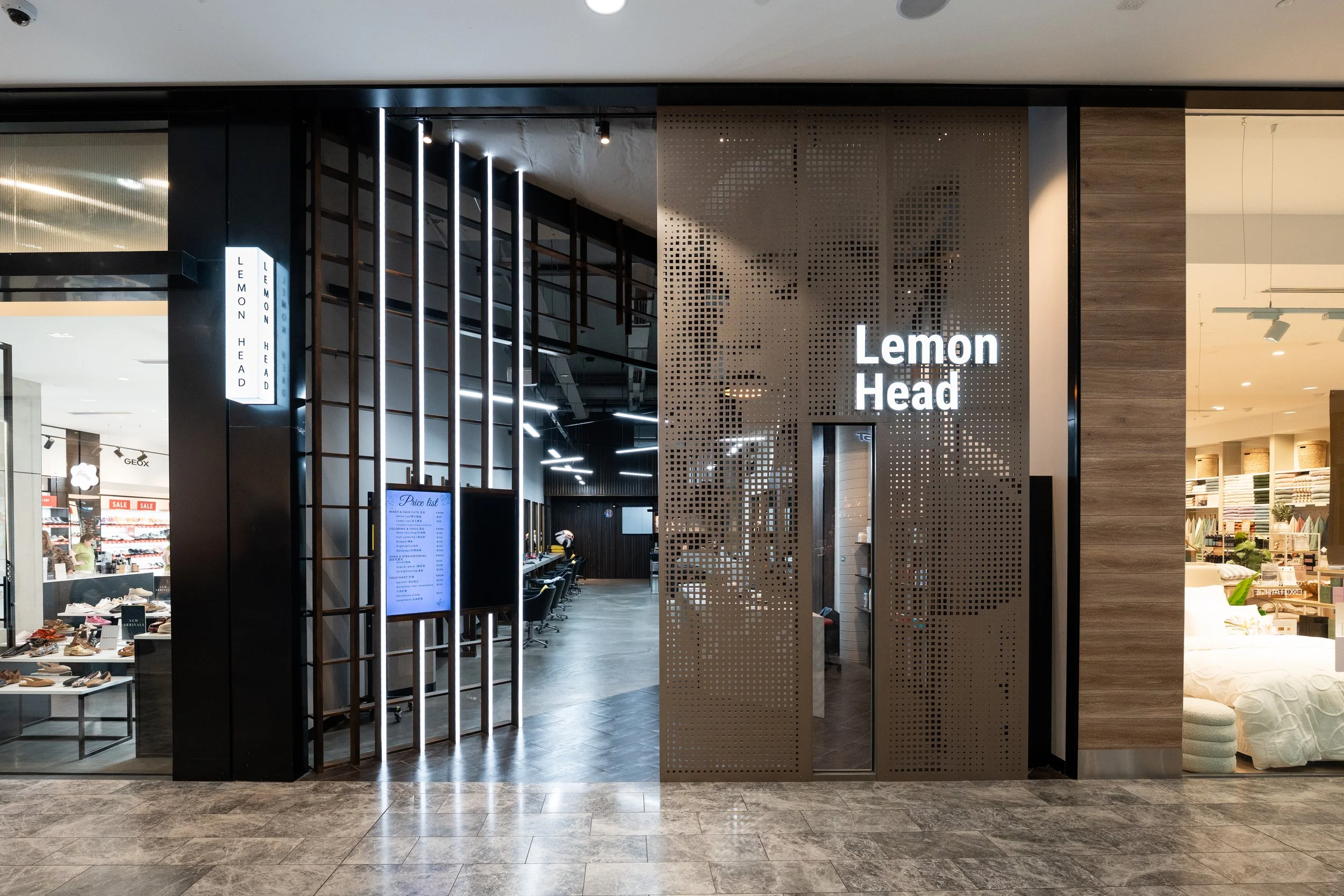 Entrance to the store 'Lemon Head' with illuminated sign, wooden and perforated metal walls, and store interior visible through the entrance.