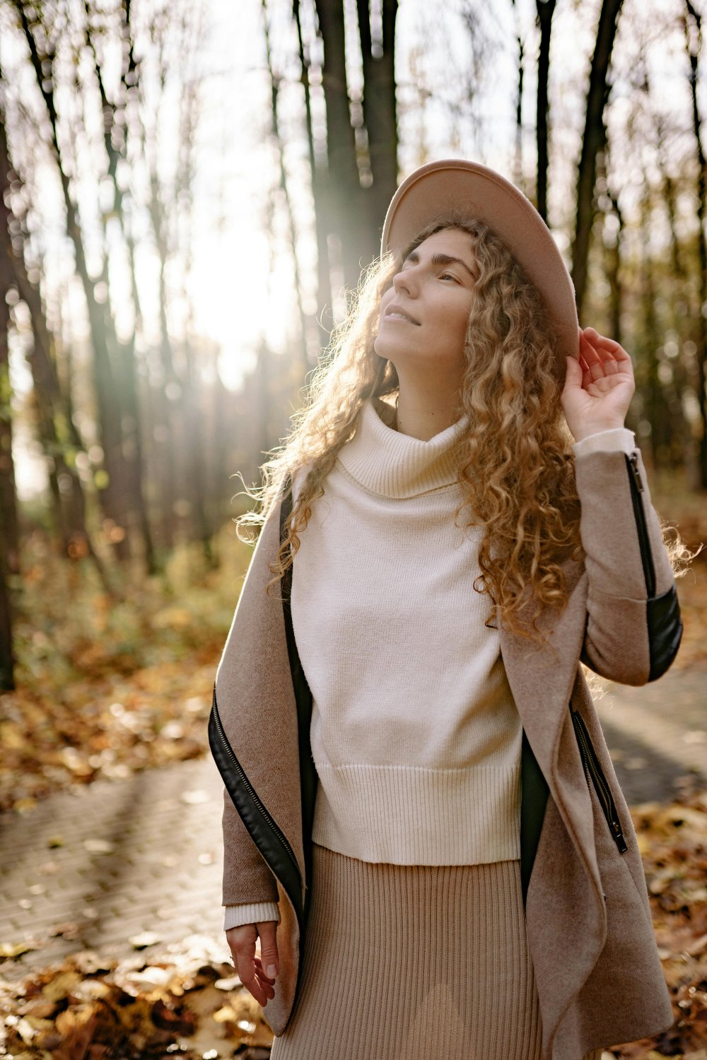 Woman standing in sunlight in the woods, eyes closed, feeling peaceful. | EMDR side effects