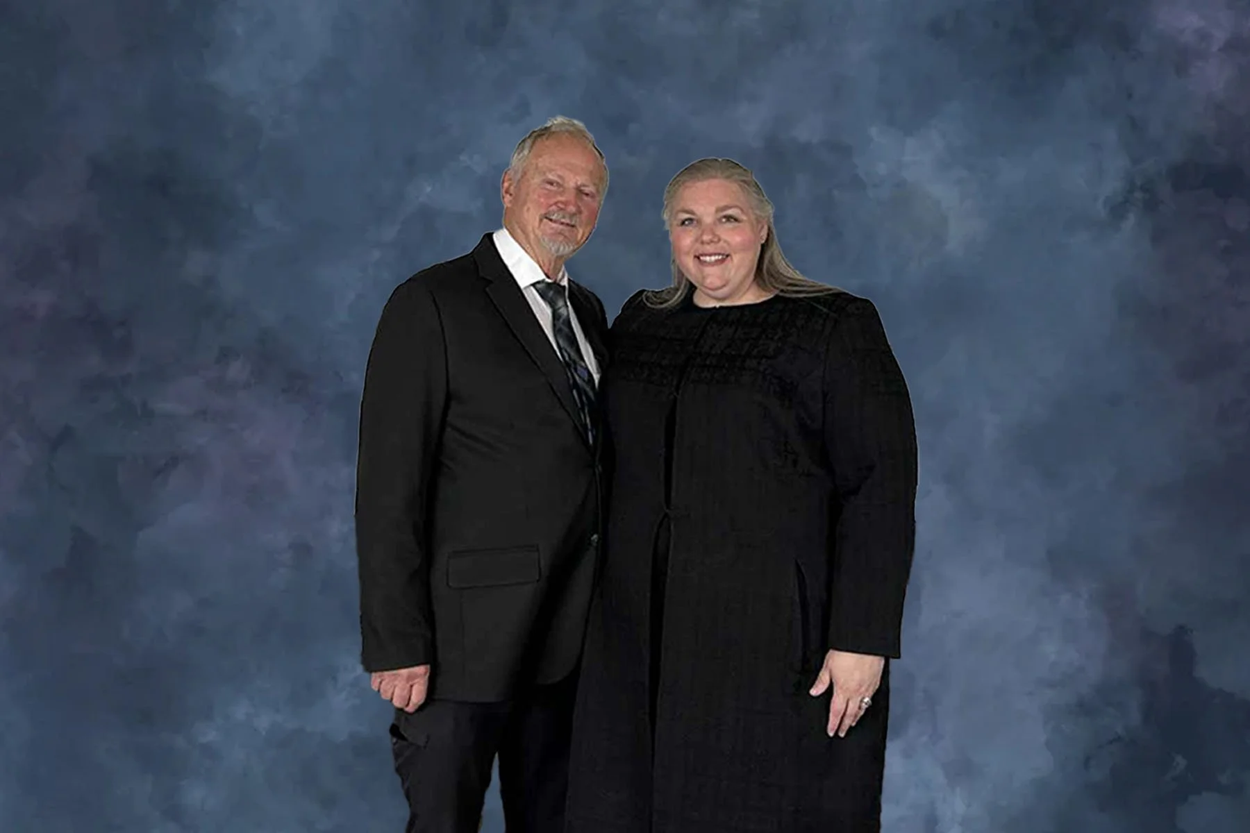 Pastor Amy and Ivan in formal attire posing together against a blue textured background.