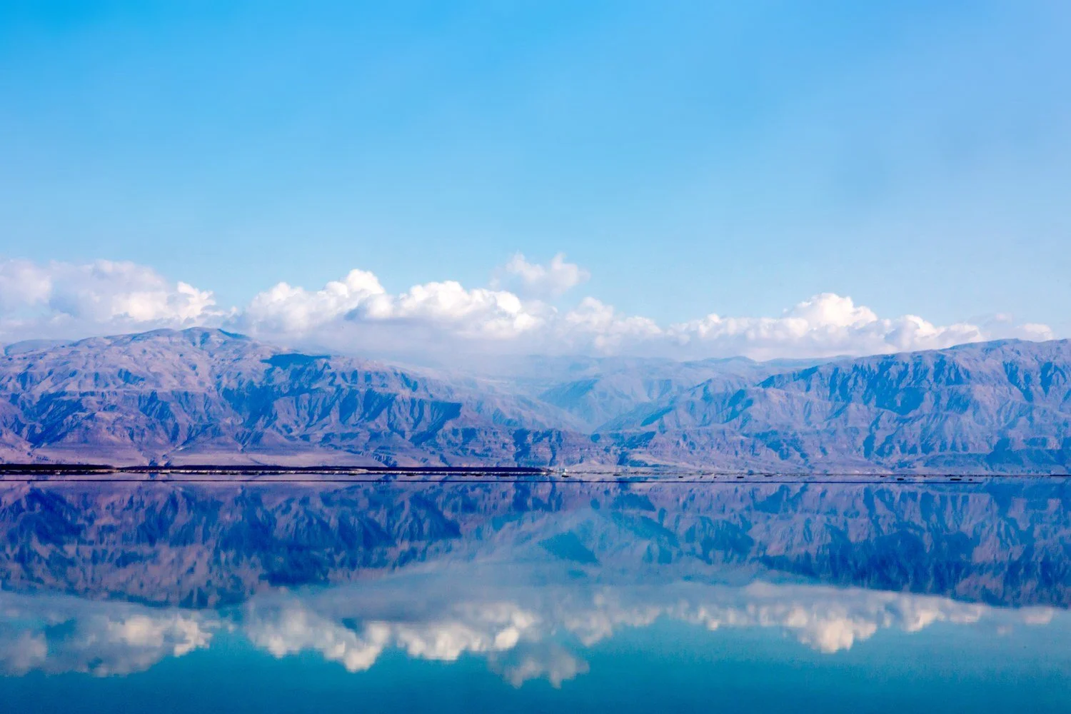 Mountains and clouds reflected in the still surface of the Dead Sea